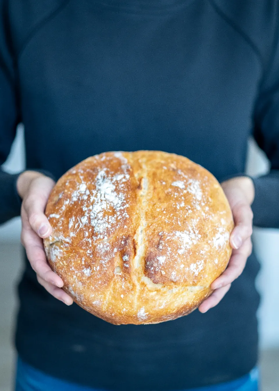 Mâini care țin o pâine rotundă, abia scoasă din cuptor